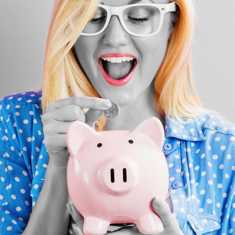 A woman putting money in a piggy bank