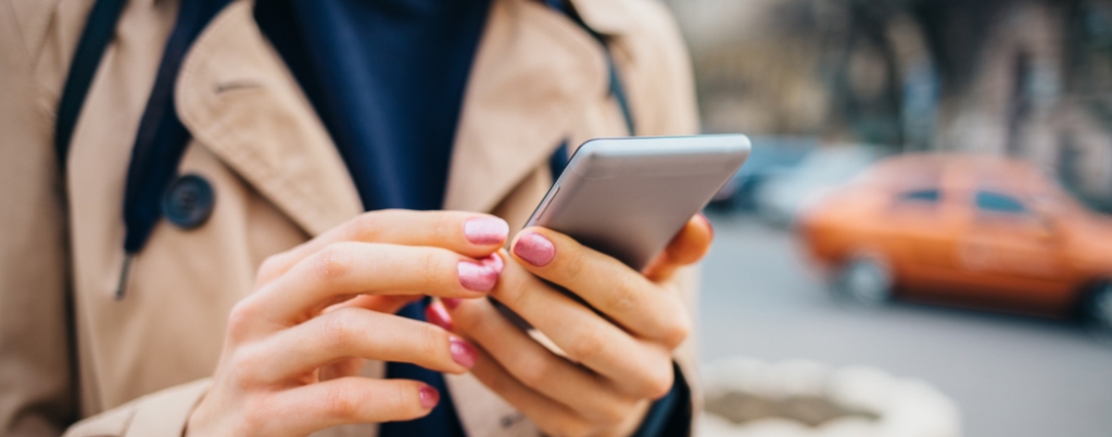 A lady uses her phone to research a brand whilst walking down the street