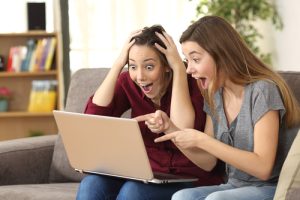 A two girls excited by what they are seeing on a laptop