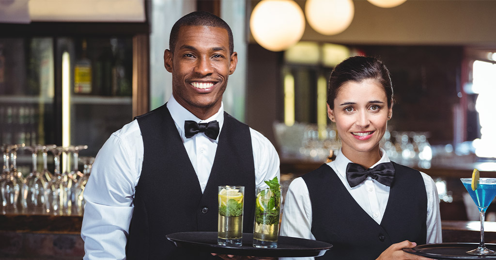 A man and a woman serving drinks at a bar