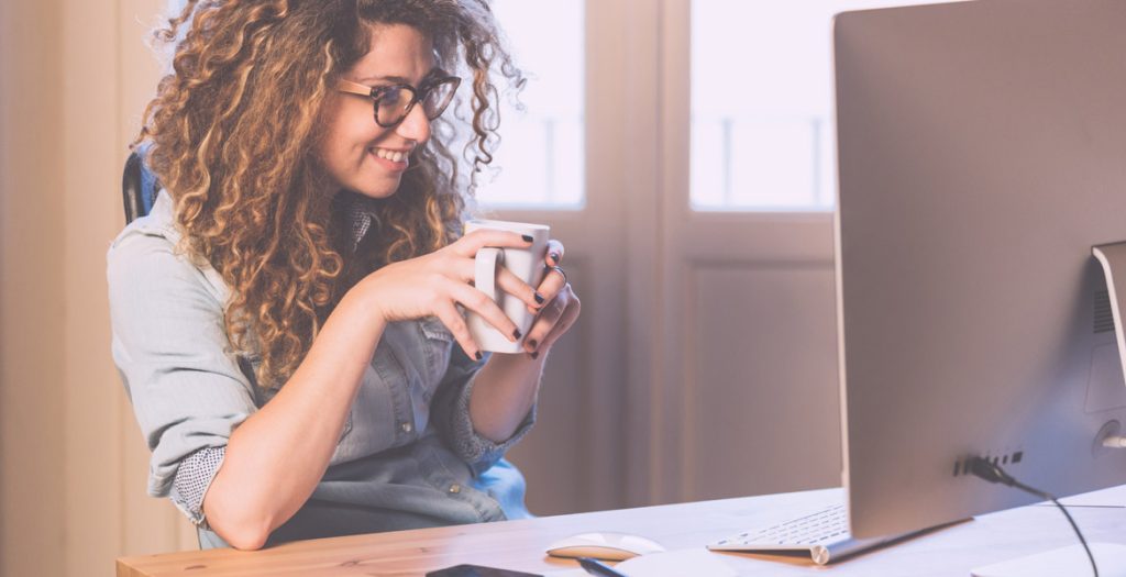 Woman sitting at desk smiling at computer screen