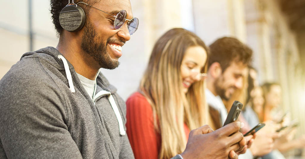 A group of young adults playing on their phones.