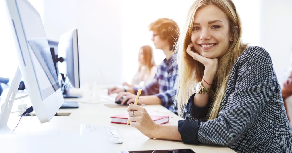 Young women sat at her desk with computer and pencil