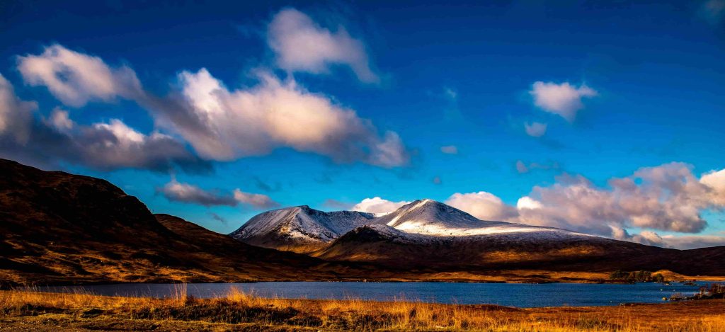 Glencoe landscape with snow-capped mountains and body of water.