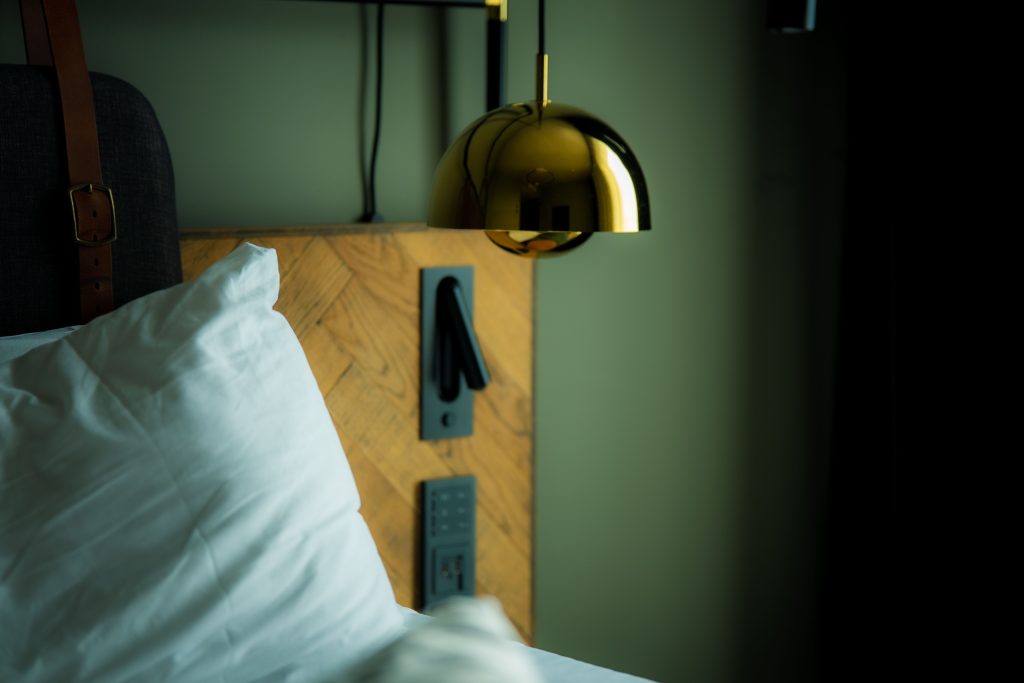 Hotel bed with lamp, lightswitch and green wall